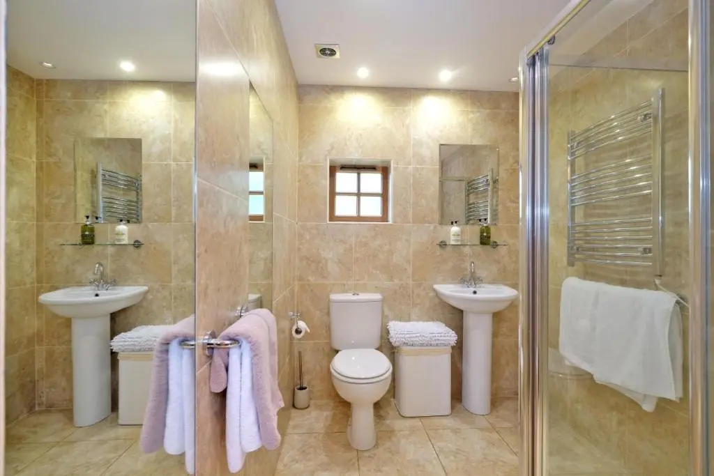 a bathroom with a toilet and two sinks and a shower at Entire unique tiny house - Moss Cabin in Banff