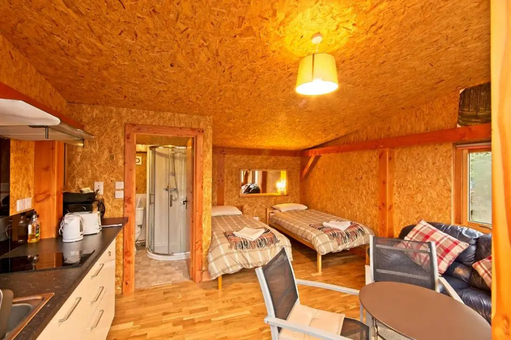 a kitchen and living room in a log cabin at Caledonian Glamping in Cannich