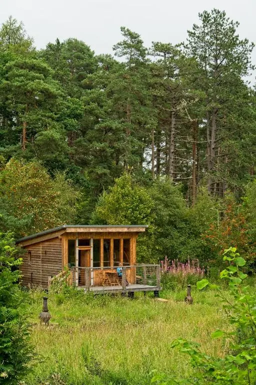 a small wooden cabin in a field with trees at Caledonian Glamping in Cannich