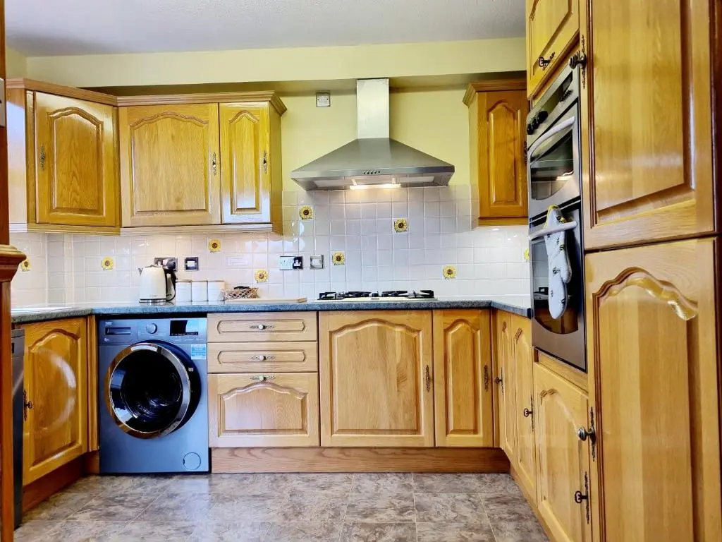 a kitchen with wooden cabinets and a washer and dryer at Inverness City 3 bedroom house free parking in Inverness