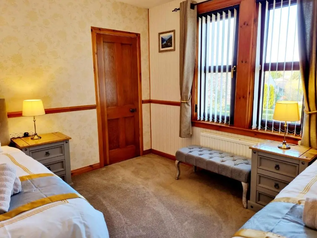 a bedroom with two beds and two windows at Inverness City 3 bedroom house free parking in Inverness