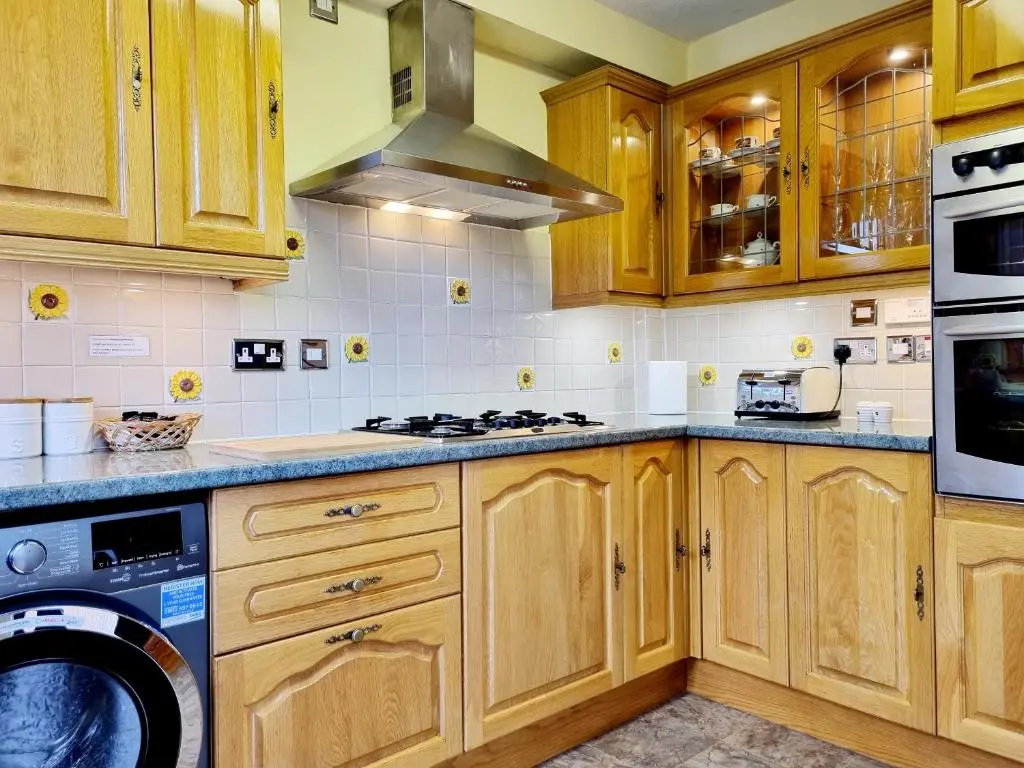 a kitchen with wooden cabinets and a washer and dryer at Inverness City 3 bedroom house free parking in Inverness
