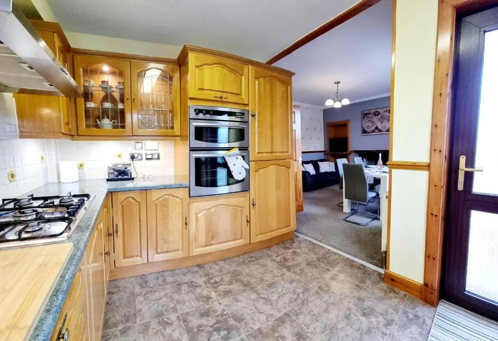 a kitchen with wooden cabinets and a stove top oven at Inverness City 3 bedroom house free parking in Inverness