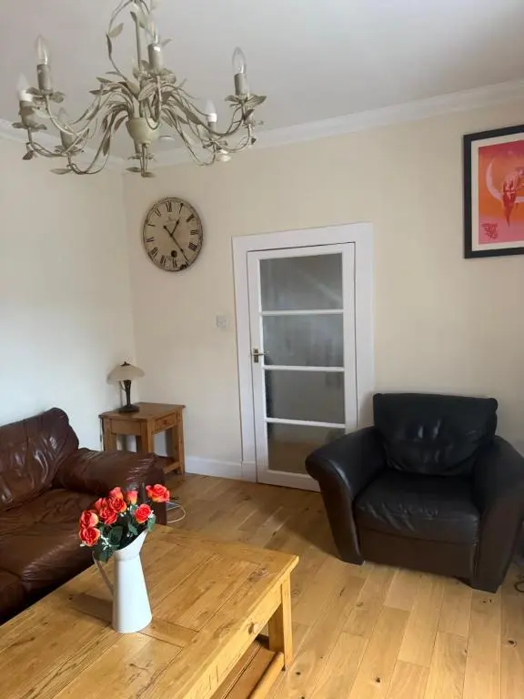 a living room with two leather couches and a clock at Riverside Cottage City Centre in Inverness