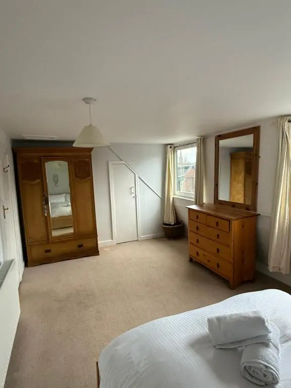 a bedroom with a bed and a dresser and a mirror at Riverside Cottage City Centre in Inverness
