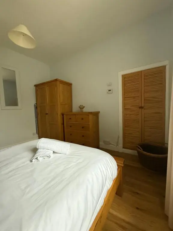 a bedroom with a white bed and a wooden dresser at Riverside Cottage City Centre in Inverness