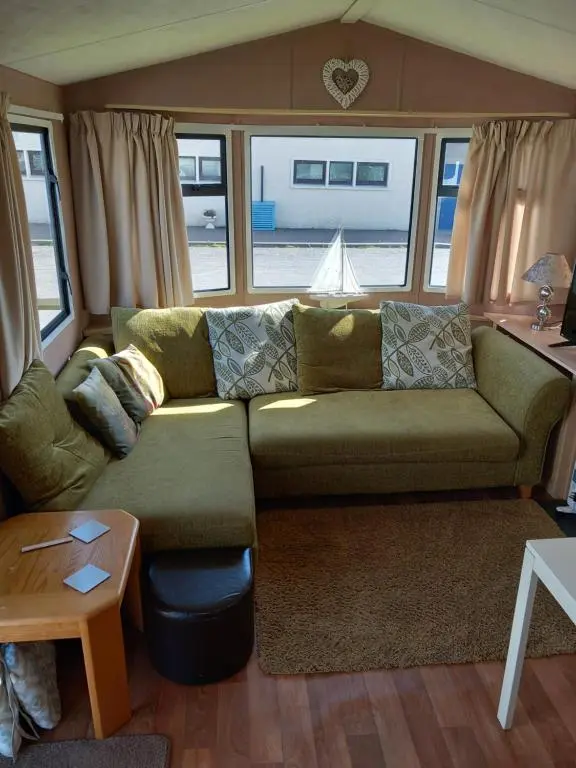 a living room with a green couch and a table at Melody Brooks Caravan Park in Portknockie