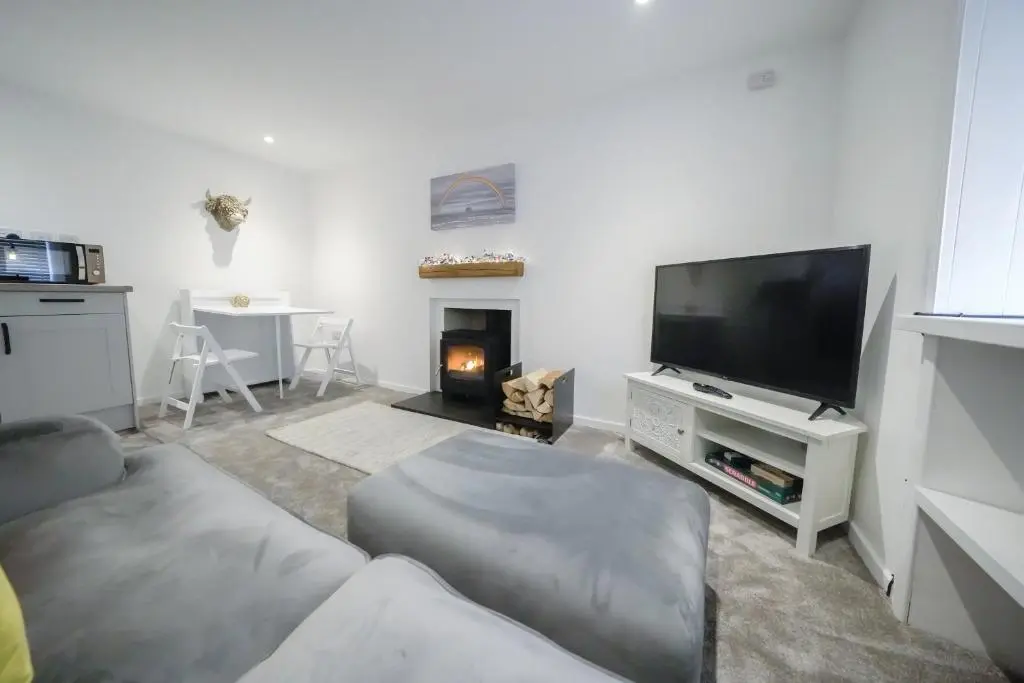 a living room with a couch and a tv at The Wee House by the Sea in Balintore