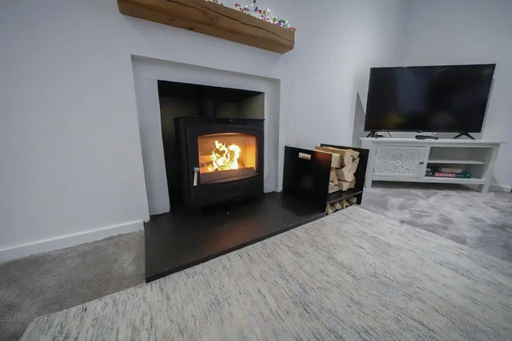 a living room with a fireplace and a tv at The Wee House by the Sea in Balintore
