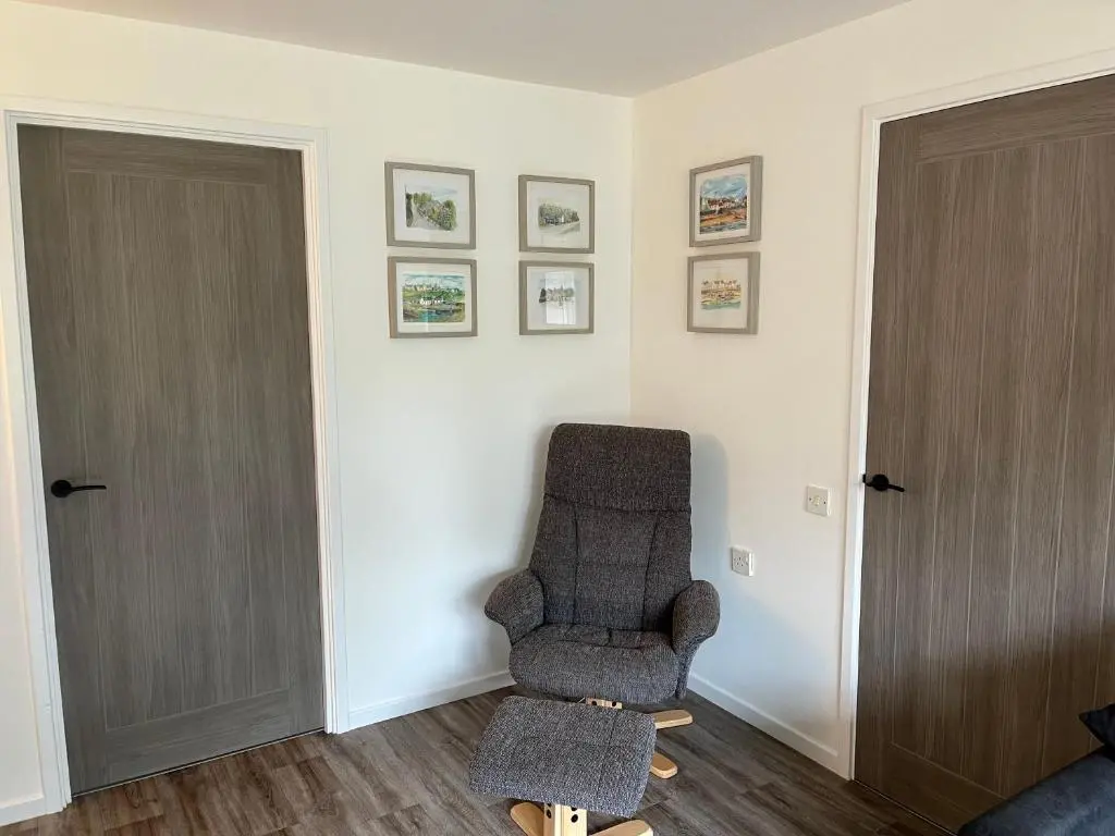 a chair sitting in a room next to two doors at The Wee Hoose near Loch Ness, private garden, private parking in Drumnadrochit