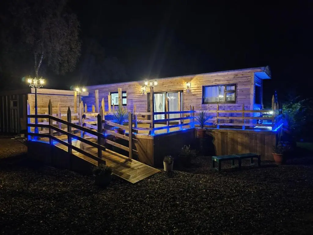 a wooden cabin with blue lights on it at night at Highland Retreats Cannich in Cannich