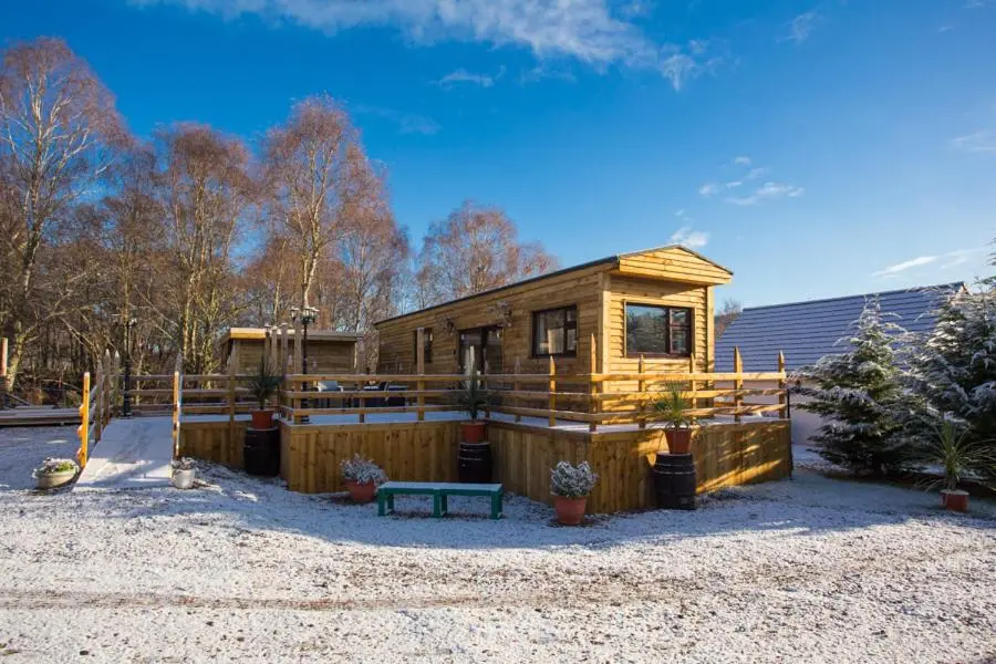 a small wooden house with a bench in front of it at Highland Retreats Cannich in Cannich