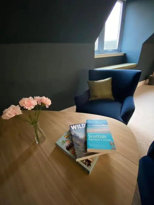 a table with books and a vase of flowers on it at Highland Hideaway in secluded riverside location in Garve