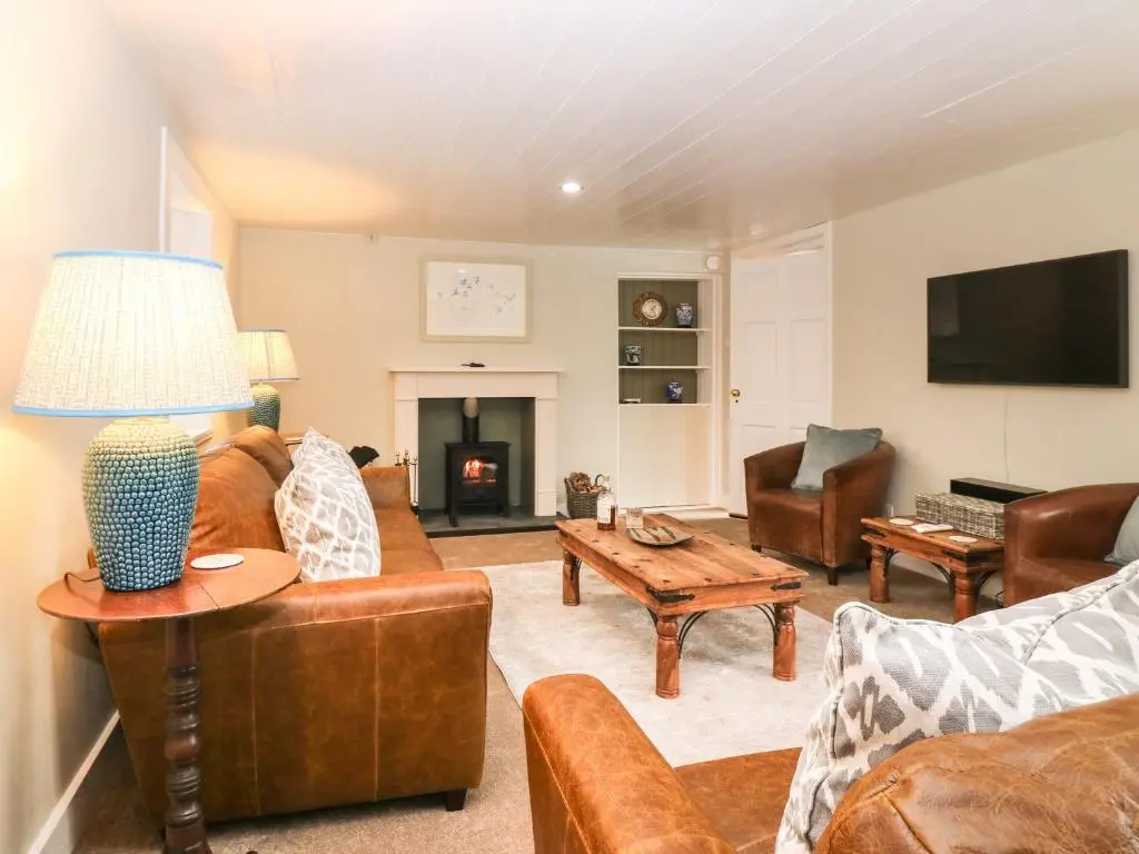 a living room with leather furniture and a tv at Garden Cottage in Elgin