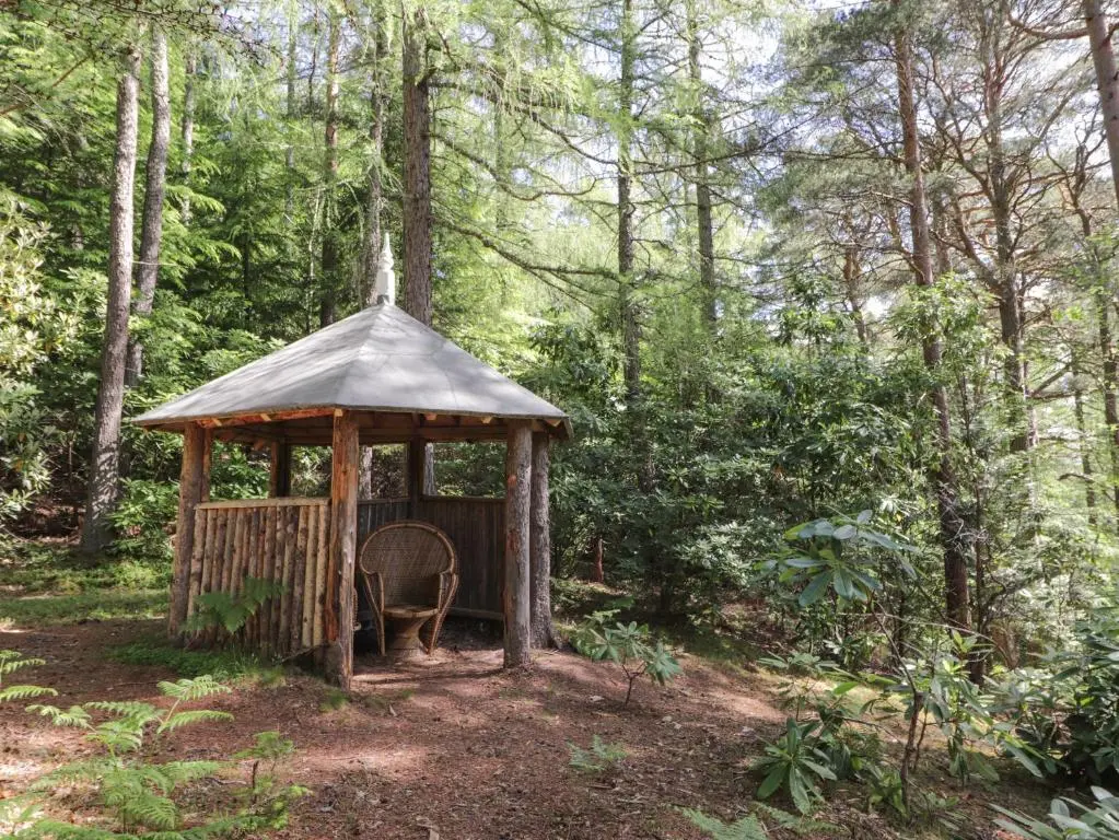 a gazebo with a chair in the woods at Garden Cottage in Elgin
