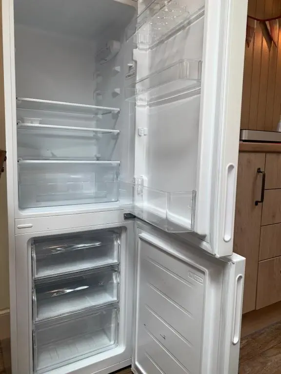 an empty refrigerator with its door open in a kitchen at The Stable - NC500 in Wick