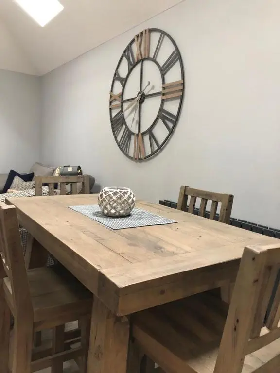 a wooden table with a large clock on the wall at The Store by Caithness Luxury Apartments NC500 - Luxury modern conversion with open plan living - Sleeps 4 in Wick