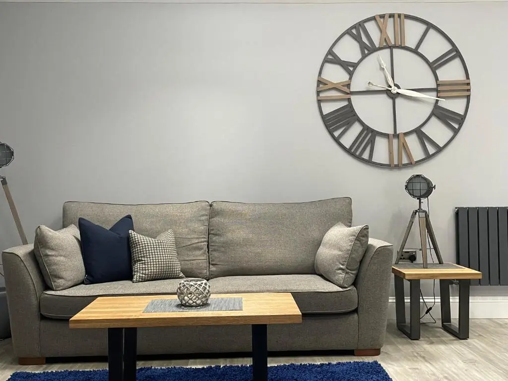 a living room with a couch and a large clock on the wall at The Store by Caithness Luxury Apartments NC500 - Luxury modern conversion with open plan living - Sleeps 4 in Wick