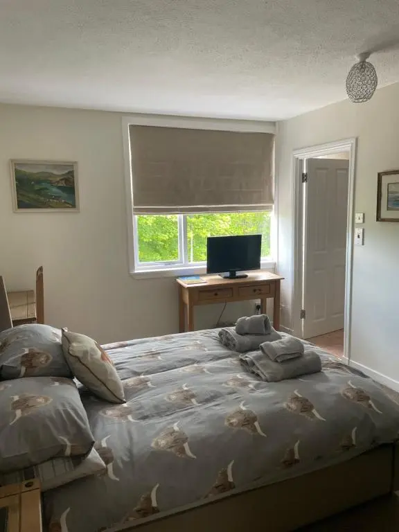 a bedroom with a bed and a desk with a computer at Charleston Apartment Self Catering 5 min drive from town centre in Inverness