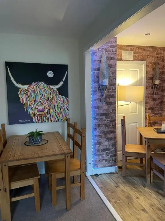a dining room with a table and a painting of a bull at Charleston Apartment Self Catering 5 min drive from town centre in Inverness
