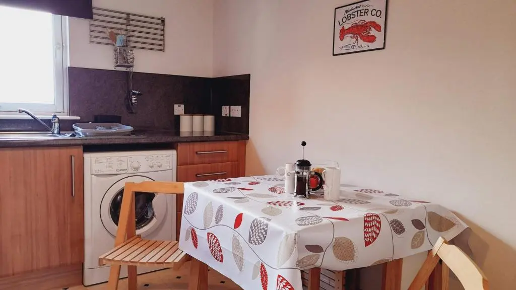 a kitchen with a table and a washing machine at Beauly Holiday Home in Beauly