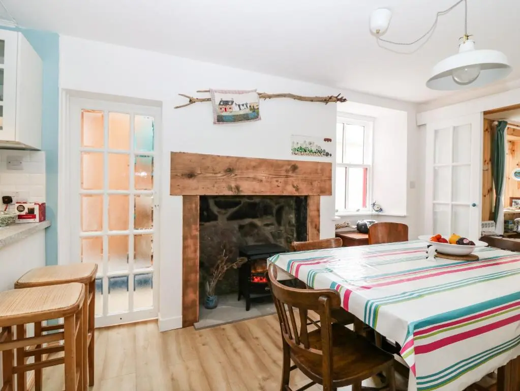 a dining room with a table and a fireplace at Dookers' Hoose in Buckie