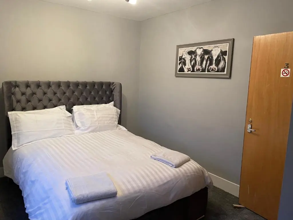 a bedroom with a large bed with white sheets at Commercial Hotel (Insch) in Insch