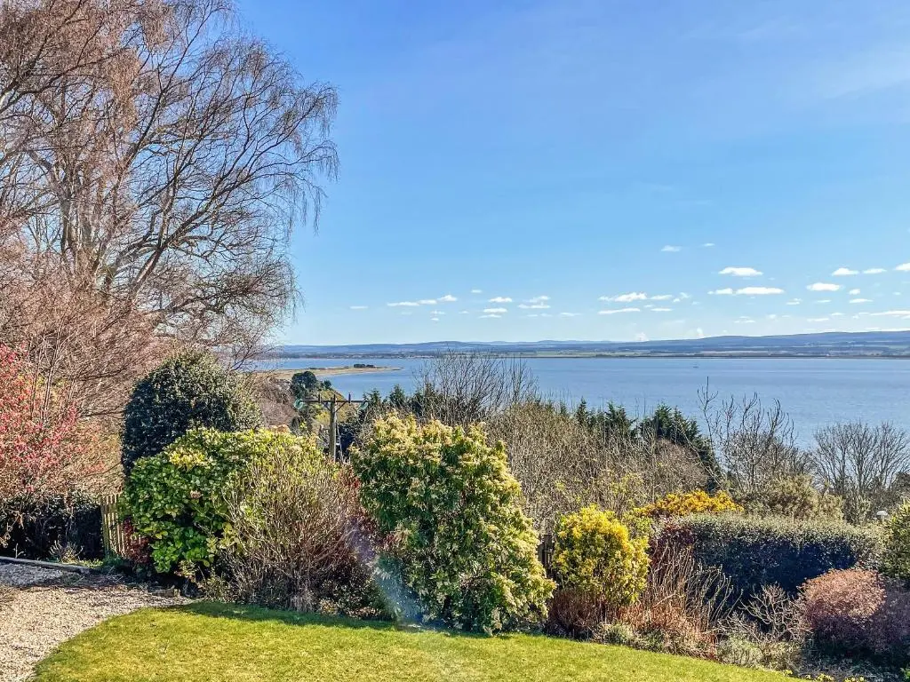 a garden with a view of a body of water at Chanonry View Holiday Cottage in Fortrose