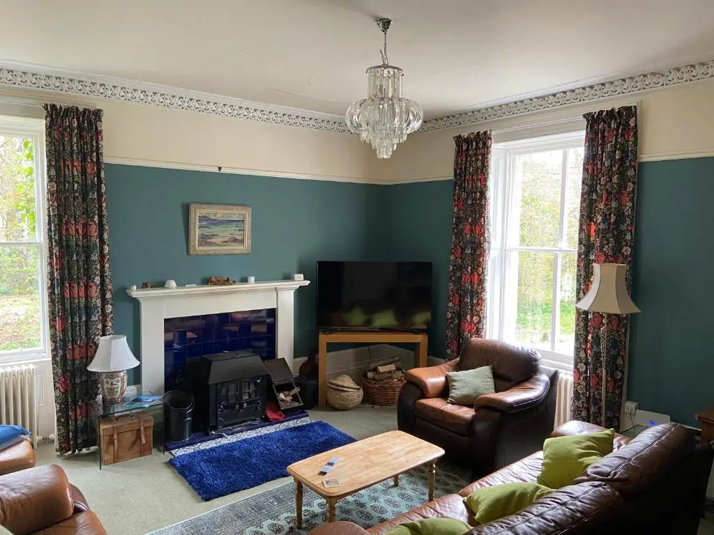 a living room with a couch and a fireplace at Beautiful Listed Mansion with incredible woodland views in Huntly