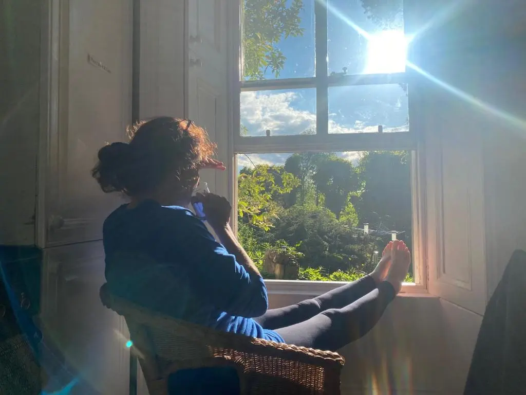 a woman sitting in a chair looking out of a window at Beautiful Listed Mansion with incredible woodland views in Huntly
