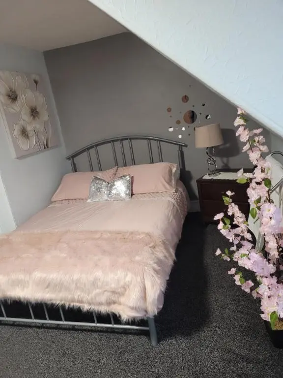 a bedroom with a bed with pink pillows and flowers at White Horse Hotel in Strichen