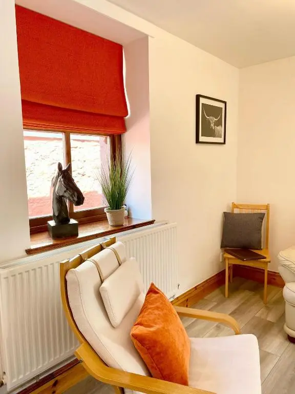 a living room with a chair and a window at The Smiddy in Inverness