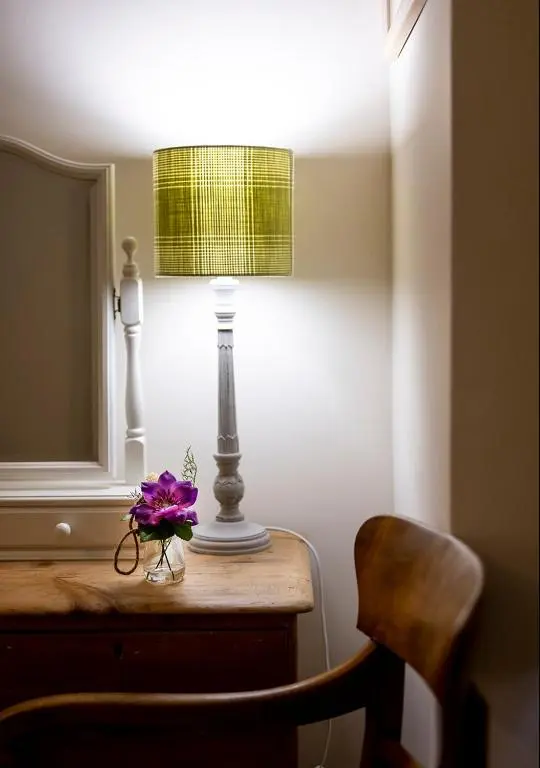 a table with a lamp and a purple flower on it at The Hideaway in Inverness