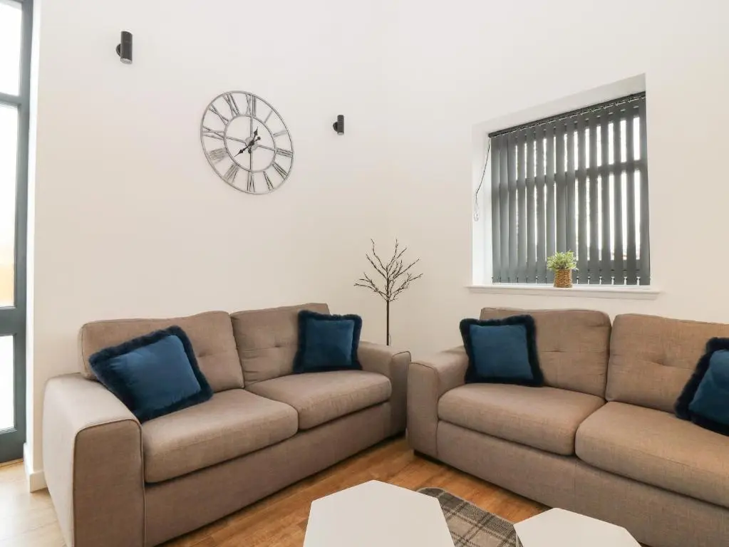 a living room with two couches and a clock on the wall at The Dance Hall, The Institute Executive Apartments in Keith