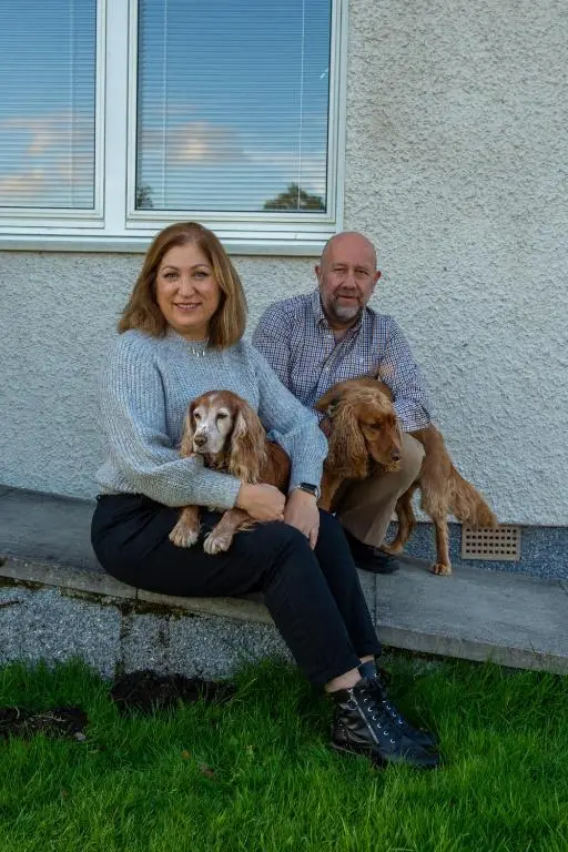 a man and a woman sitting on a curb with two dogs at Cuillich Mill Bed and Breakfast in the Highlands in Alness