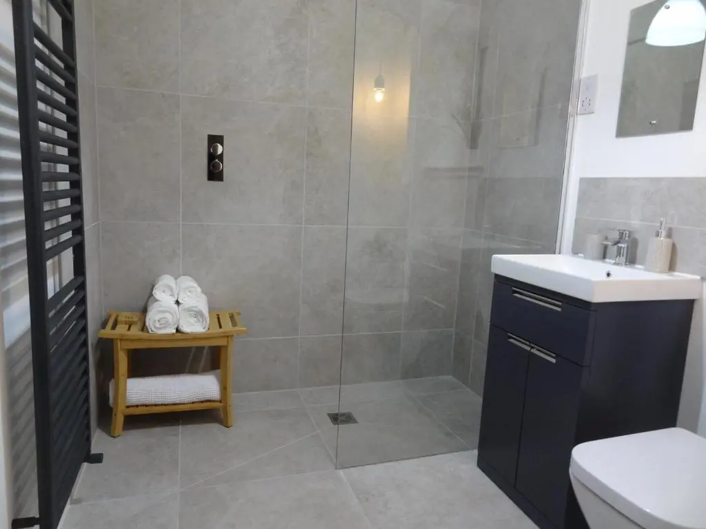 a bathroom with a shower with a sink and a toilet at Sawmill Cottage in Grantown on Spey