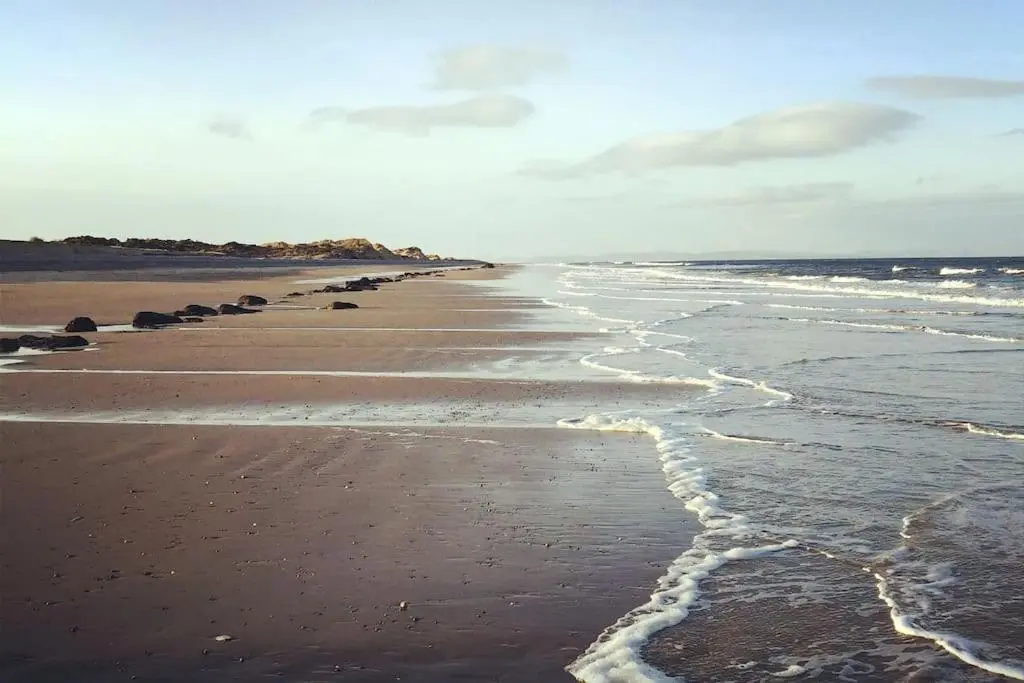 a beach with waves coming in from the ocean at The Presbytery, Forres in Forres