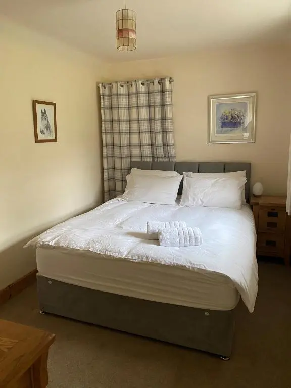 a bedroom with a bed with white sheets and pillows at Cosy Cottage in beautiful Royal Deeside in Aboyne
