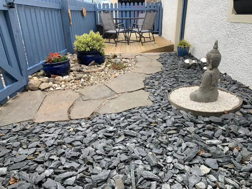 a patio with a statue of a cat sitting on a rock at Zen Cottage Cullen - Sleeps 4 Garden & Pets Ok in Cullen