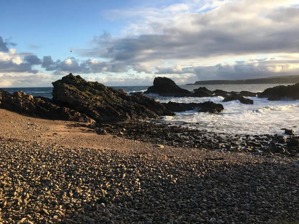 a rocky beach with rocks in the water at Zen Cottage Cullen - Sleeps 4 Garden & Pets Ok in Cullen