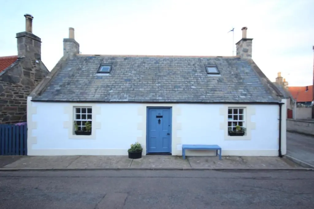 a white house with a blue door and a bench at Zen Cottage Cullen - Sleeps 4 Garden & Pets Ok in Cullen