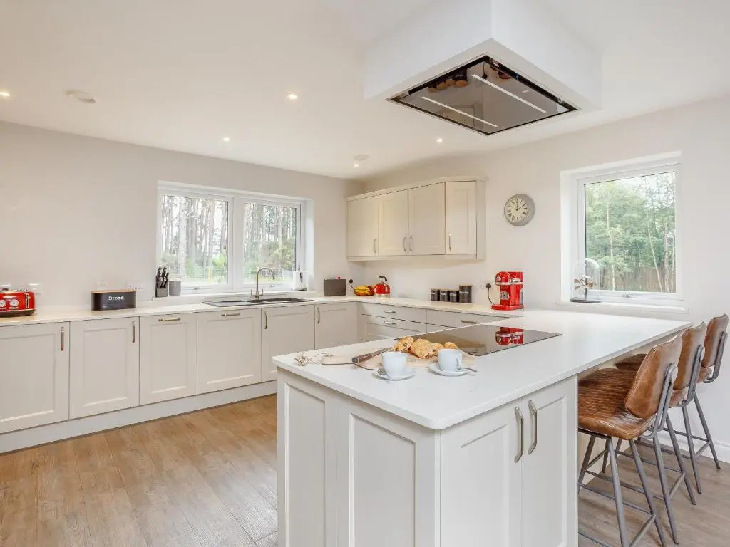 a kitchen with white cabinets and a large island at Strathclaggan in Aberlour