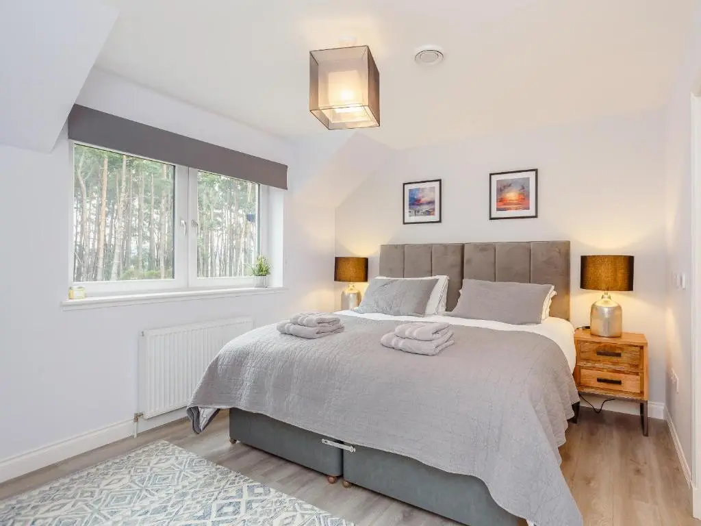 a bedroom with a large bed and a window at Strathclaggan in Aberlour