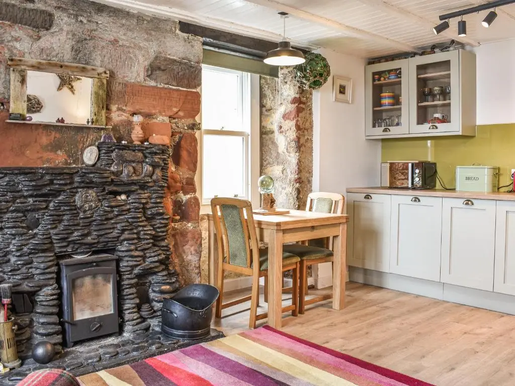 a kitchen with a table and a stone fireplace at The Windowky in Gardenstown
