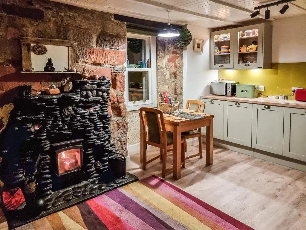 a kitchen with a fireplace in the middle of a room at The Windowky in Gardenstown