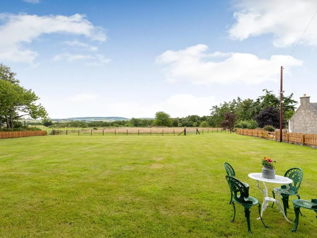 a table and chairs in a grass field at Glen Nevis Cottage in Port Elphinstone