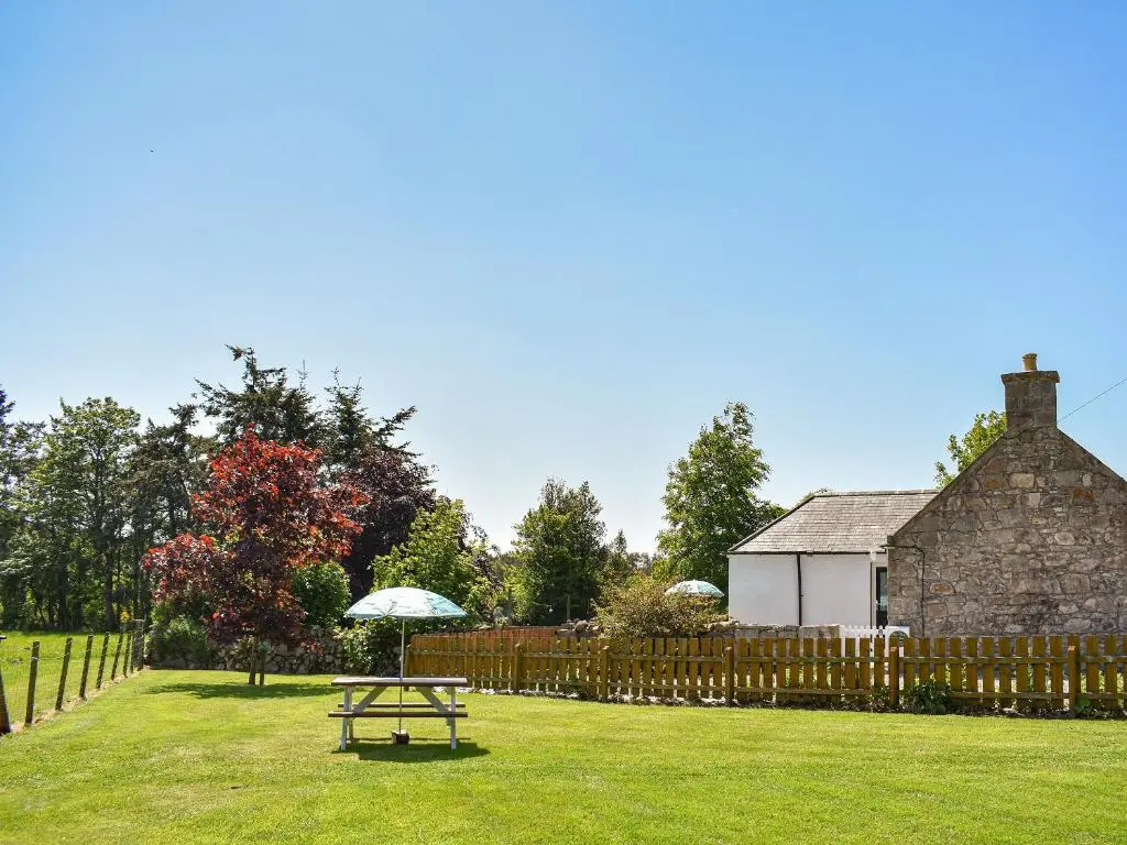 a picnic table in the grass in front of a house at Glen Nevis Cottage in Port Elphinstone