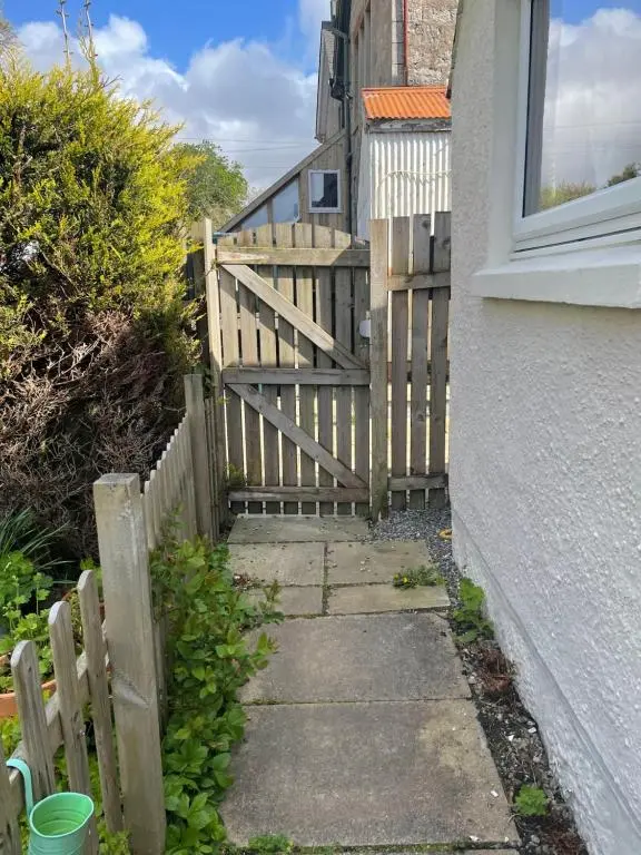 a wooden fence next to a sidewalk next to a house at Newsagents Flat in Lairg