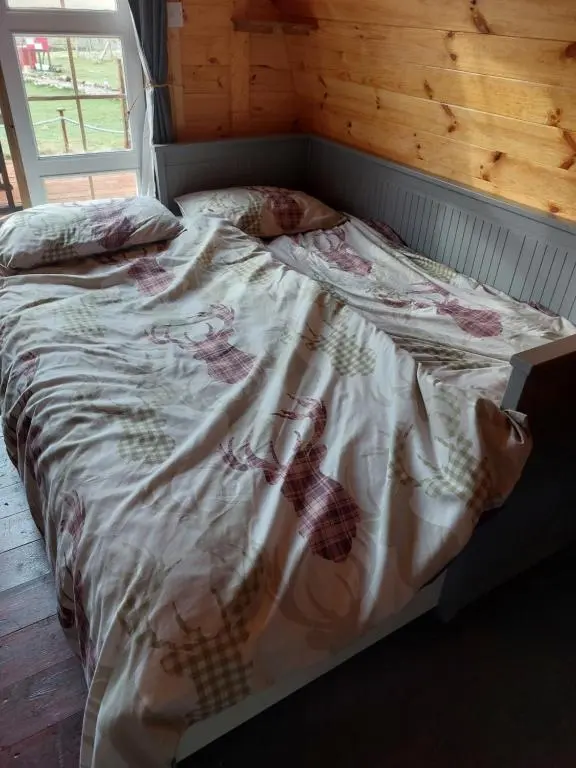 an unmade bed in a room with a wooden wall at Pod 4 in Skail