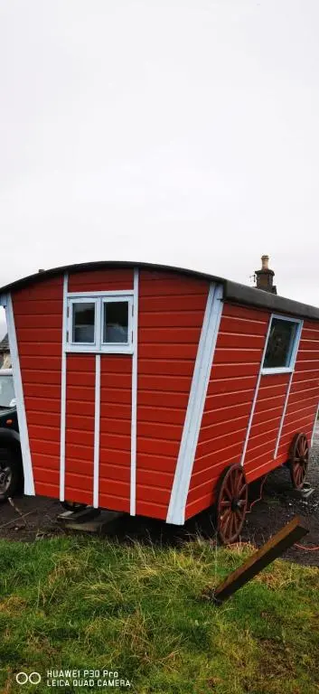 a red and white trailer parked in a field at Gypsy hut in Newtonmore